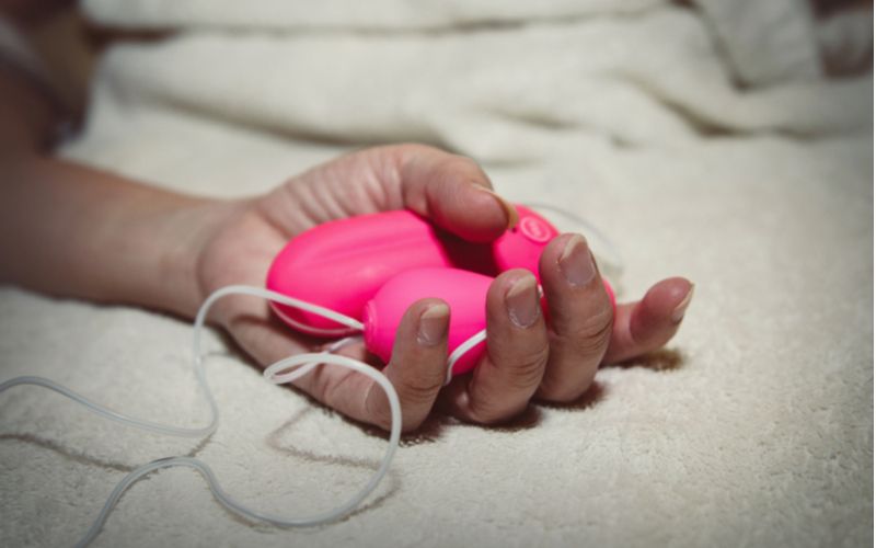 Růžové vibrační vajíčko s ovladačem v ženské ruce