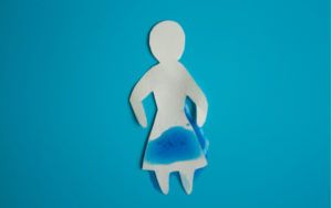 Inkontinence - papírová žena na modrém pozadí a pomočování v intimní oblasti
